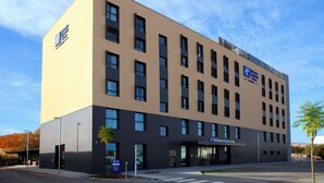 A modern hotel building with a flat facade, multiple windows, and a sign for 'Hilton Express'. - Holiday Inn Express & Suites Barcelona Sabadell by IHG (Sabadell)
