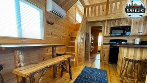 A wooden interior with a kitchen area, a dining table, and a staircase. - Alpen Bluffs Outdoor Resort (Gaylord)