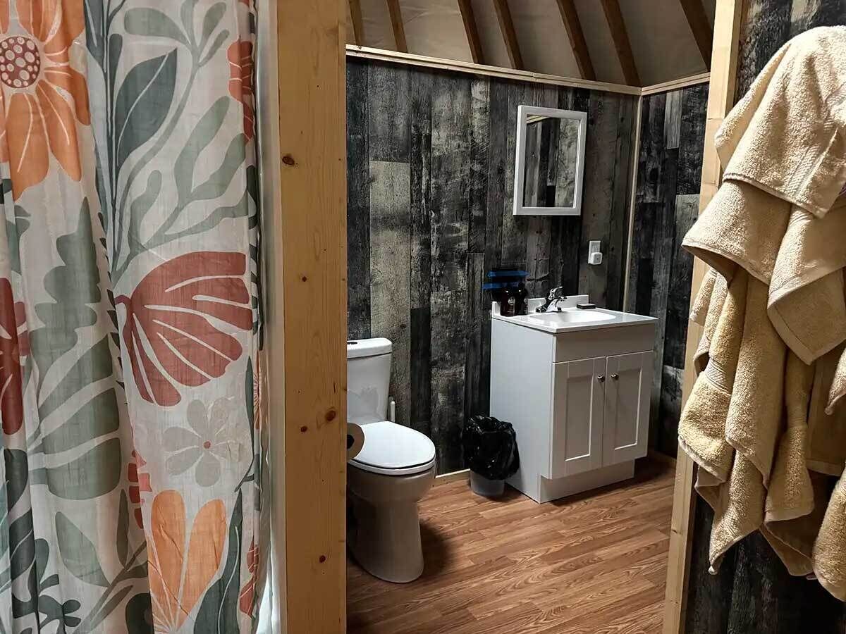 Pieni kylpyhuone, jossa on wc, pesuallas ja peili.