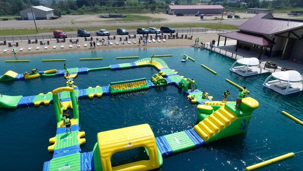 An outdoor water park with inflatable play structures and a pool. - Alpen Bluffs Outdoor Resort (Gaylord)