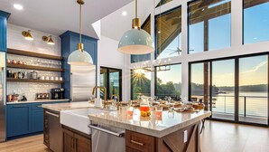 Una cocina moderna con una isla grande, armarios azules y vista a un lago.
