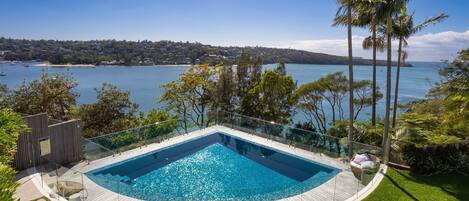 Una piscina circular infinita con vistas despejadas a una bahía y edificios lejanos.