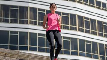 A person running up a set of outdoor stairs with a modern building in the background.
