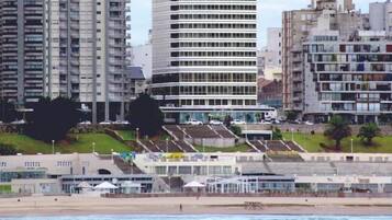 A coastal cityscape with high-rise buildings, a beach, and a stadium.
