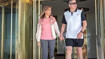 A man and a woman walking out of a building with a glass entrance.