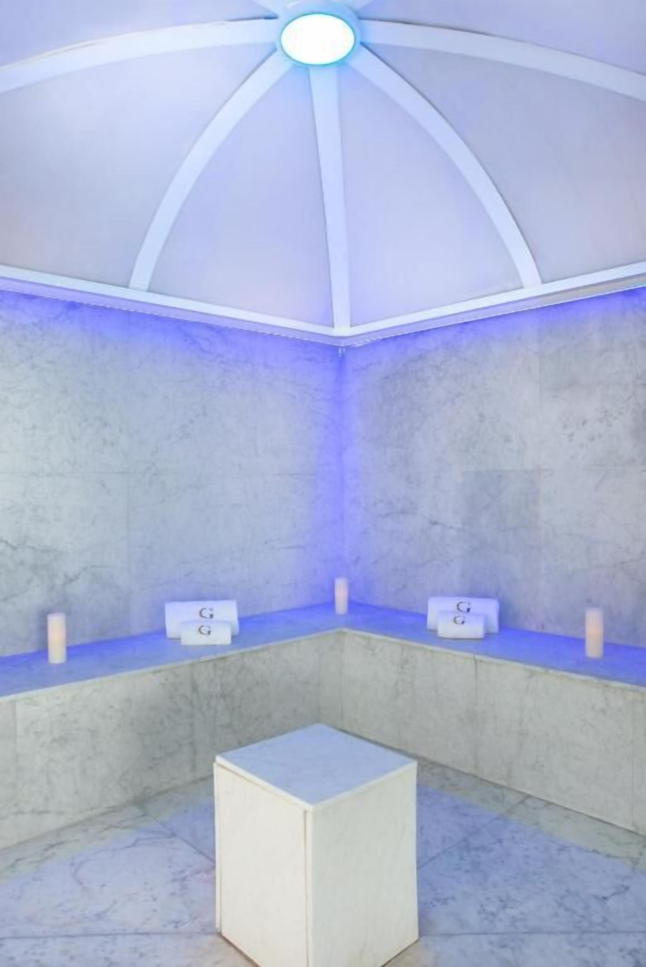 Quarto com teto abobadado, um banco branco e duas placas com letras.