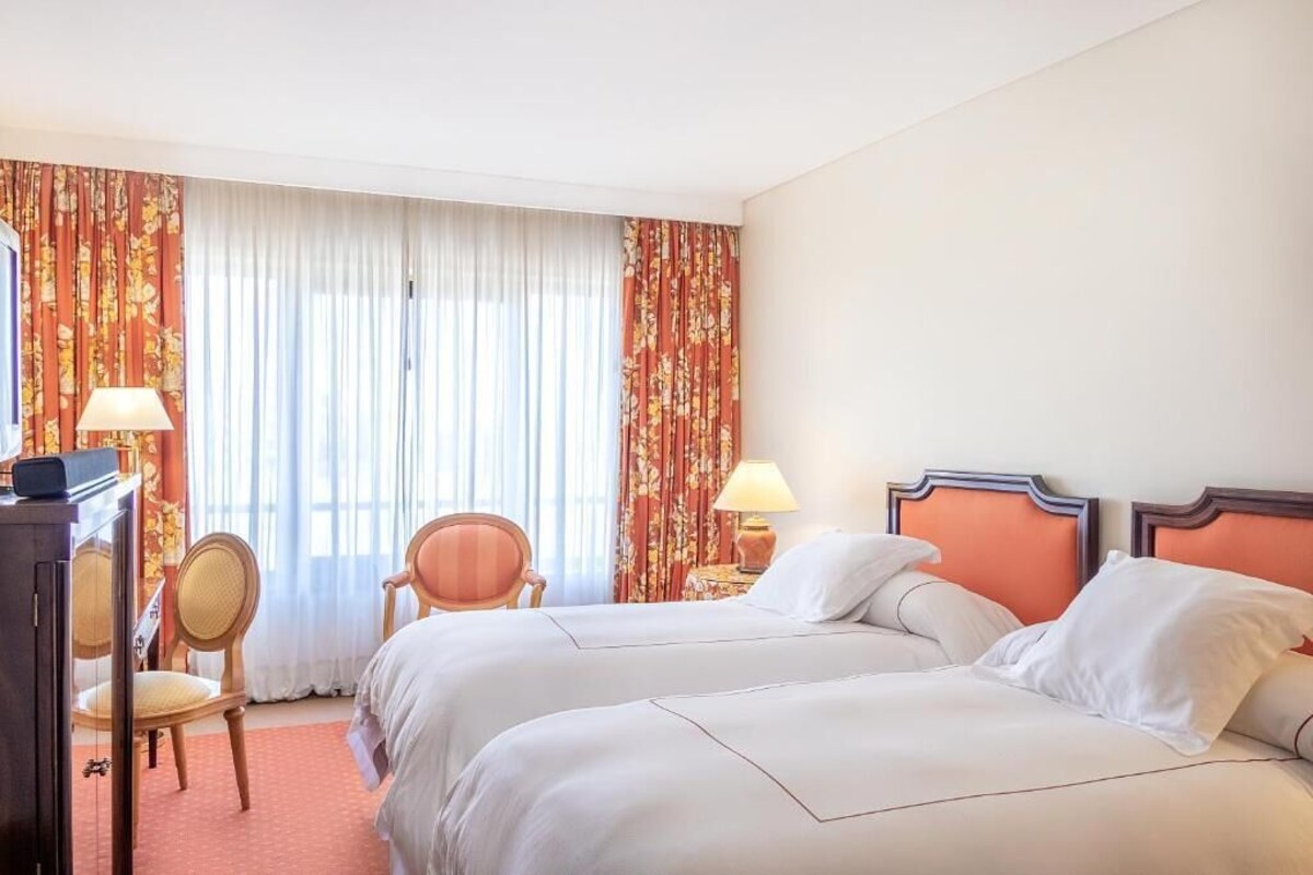 Une chambre d’hôtel avec deux lits, un bureau et une chaise.