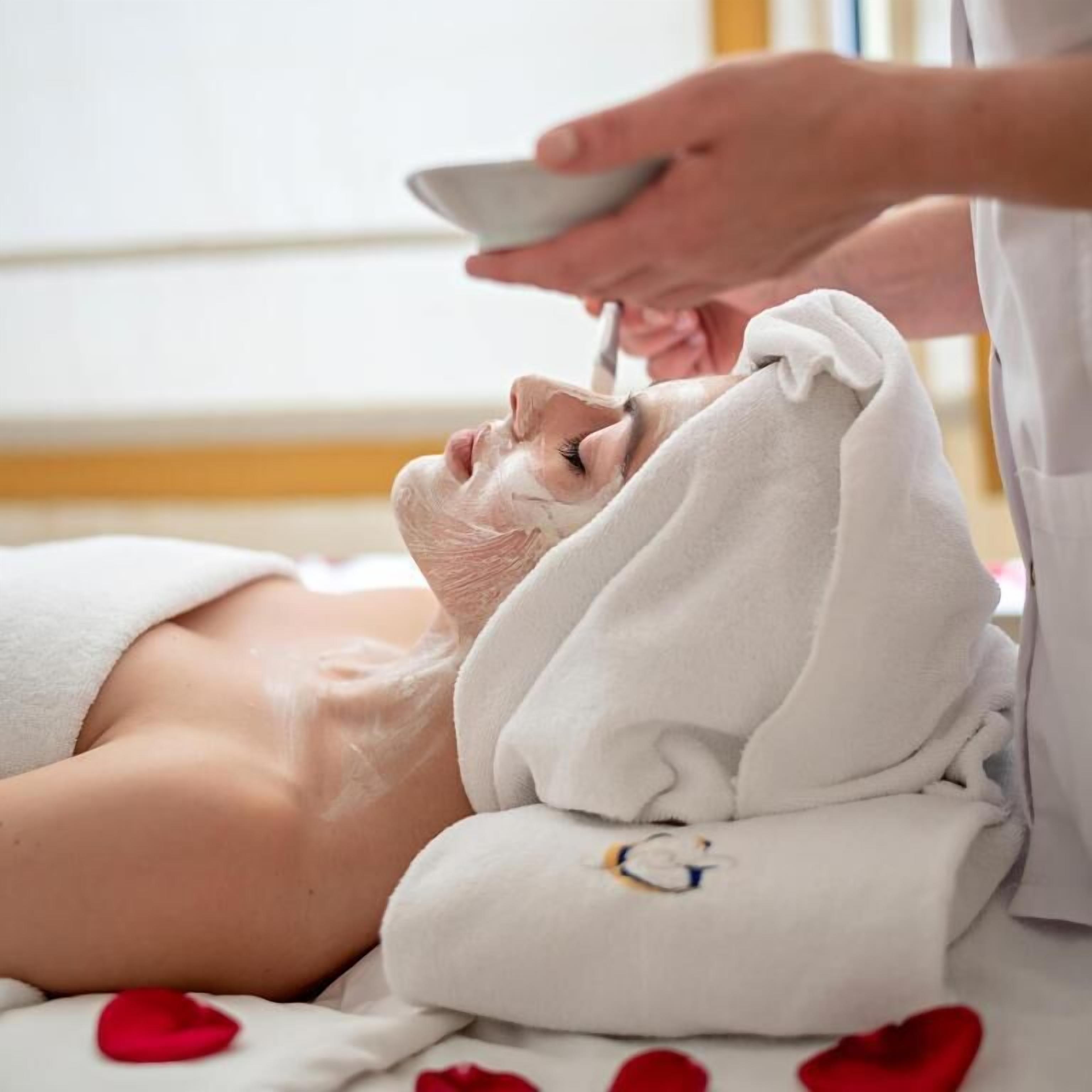 A person receiving a facial treatment with a towel wrapped around their head.