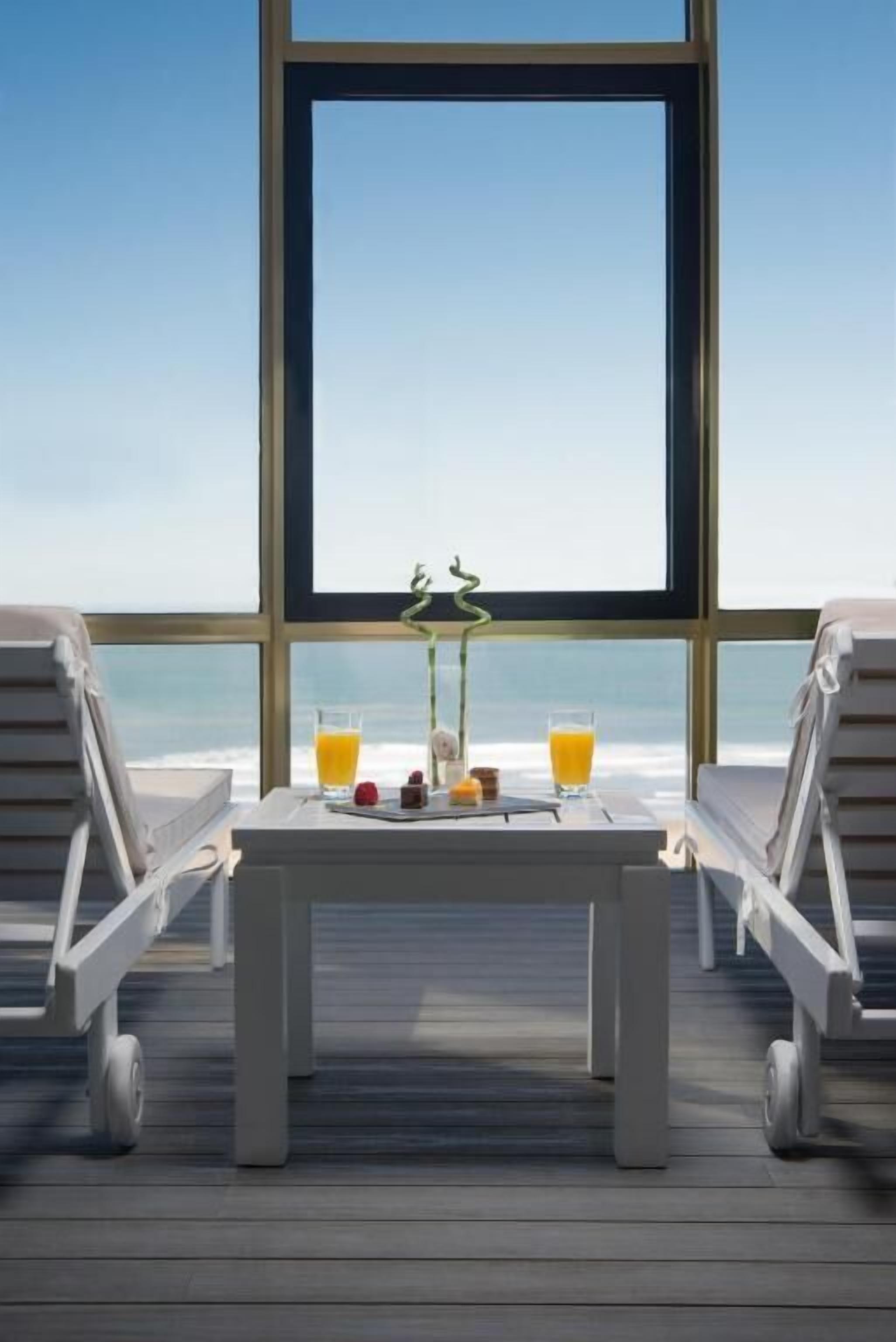 A deck with a table set for breakfast overlooking the ocean.