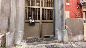 Μια μεταλλική πύλη με ένα μεταλλικό πλέγμα και ένα μικρό κουτί επιστολών τοποθετημένο στο έδαφος.