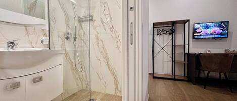 A modern bathroom with a glass-enclosed shower, a white sink, and a marble backsplash.