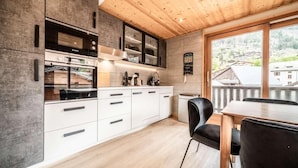 A modern kitchen with white cabinets, a Bosch oven, and a wooden ceiling.