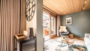 A modern living room with a large clock, a fireplace, and a view of the outside.