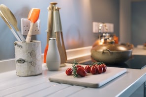 Un plan de travail de cuisine avec une planche à découper, un saladier et un récipient contenant des ustensiles.