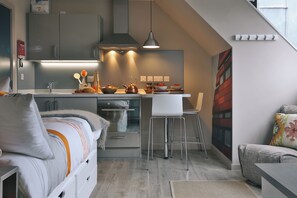 Eine moderne Küche mit Kochinsel, Deckenleuchten und einer Essecke mit einem weißen Stuhl.