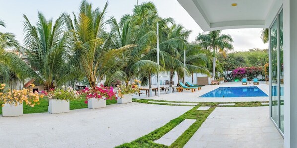 A pool area with palm trees, a swimming pool, and outdoor seating. - Casa Romero Cartagena Club de Playa (Cartagena)