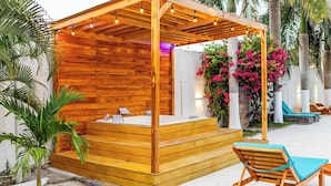 A wooden outdoor hot tub area with steps leading up to it, surrounded by lounge chairs and tropical plants. - Casa Romero Cartagena Club de Playa (Cartagena)