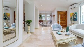 A spacious living room with a white sofa, a coffee table, and a dining area in the background. - Casa Romero Cartagena Club de Playa (Cartagena)