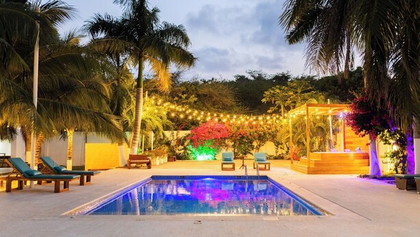 A swimming pool with lounge chairs and a wooden structure with a bench. - Casa Romero Cartagena Club de Playa (Cartagena)