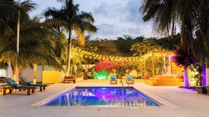 A swimming pool with lounge chairs and a wooden structure with a bench. - Casa Romero Cartagena Club de Playa (Cartagena)