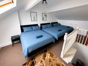 A bedroom with two beds, a white staircase, and a ceiling light fixture. - 3BR-Sleep 10– Near Stadium,Centre & M-Links - Contractors / Corporate & Families (Leeds)