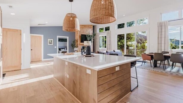 A modern kitchen with a large island, wooden cabinets, and pendant lighting. - Sauna & Cold Plunge Cabin + Mountain Wellness Retreat (Bryson City)