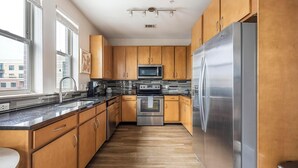 A modern kitchen with wooden cabinets, stainless steel appliances, and a large window providing natural light. - Landing | Amazing 1BD, Clubhouse, Gym (Denver)