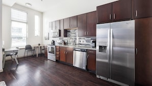 A modern kitchen with dark wood cabinets, stainless steel appliances, and a water dispenser. - Landing | Beautiful Studio, Gym, Rooftop Lounge (Denver)