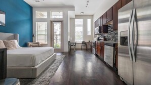 A modern apartment with a large bed, a kitchen with stainless steel appliances, and a view through the windows. - Landing | Beautiful Studio, Gym, Rooftop Lounge (Denver)