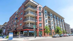 A multi-story apartment building with balconies, a ground-level restaurant, and a visible parking area. - Landing | Beautiful Studio, Gym, Rooftop Lounge (Denver)