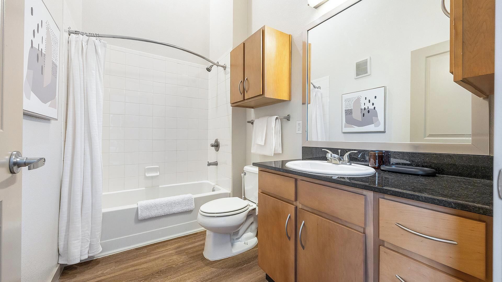 Een badkamer met een badkuip, toilet, wastafel en houten kasten.