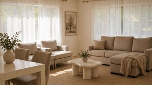 A living room with a sofa, chairs, a coffee table, and a dining table.