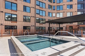A modern building with a swimming pool, large windows, and a covered outdoor area.