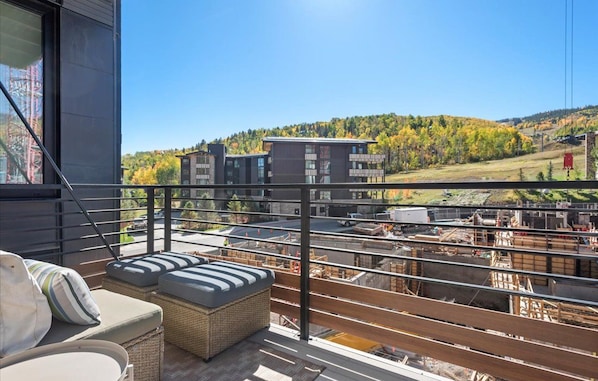 A balcony with wicker furniture, a view of a construction site, and buildings in the background.