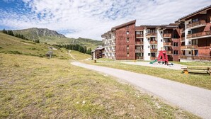 Un hôtel moderne à plusieurs étages, doté d’un télésiège et offrant une vue sur la montagne.