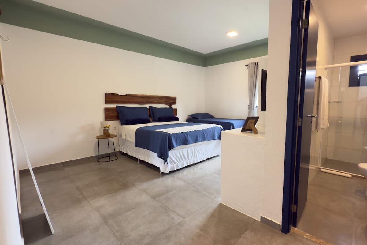 Een slaapkamer met twee bedden, een klein tafeltje en een douchehoek.