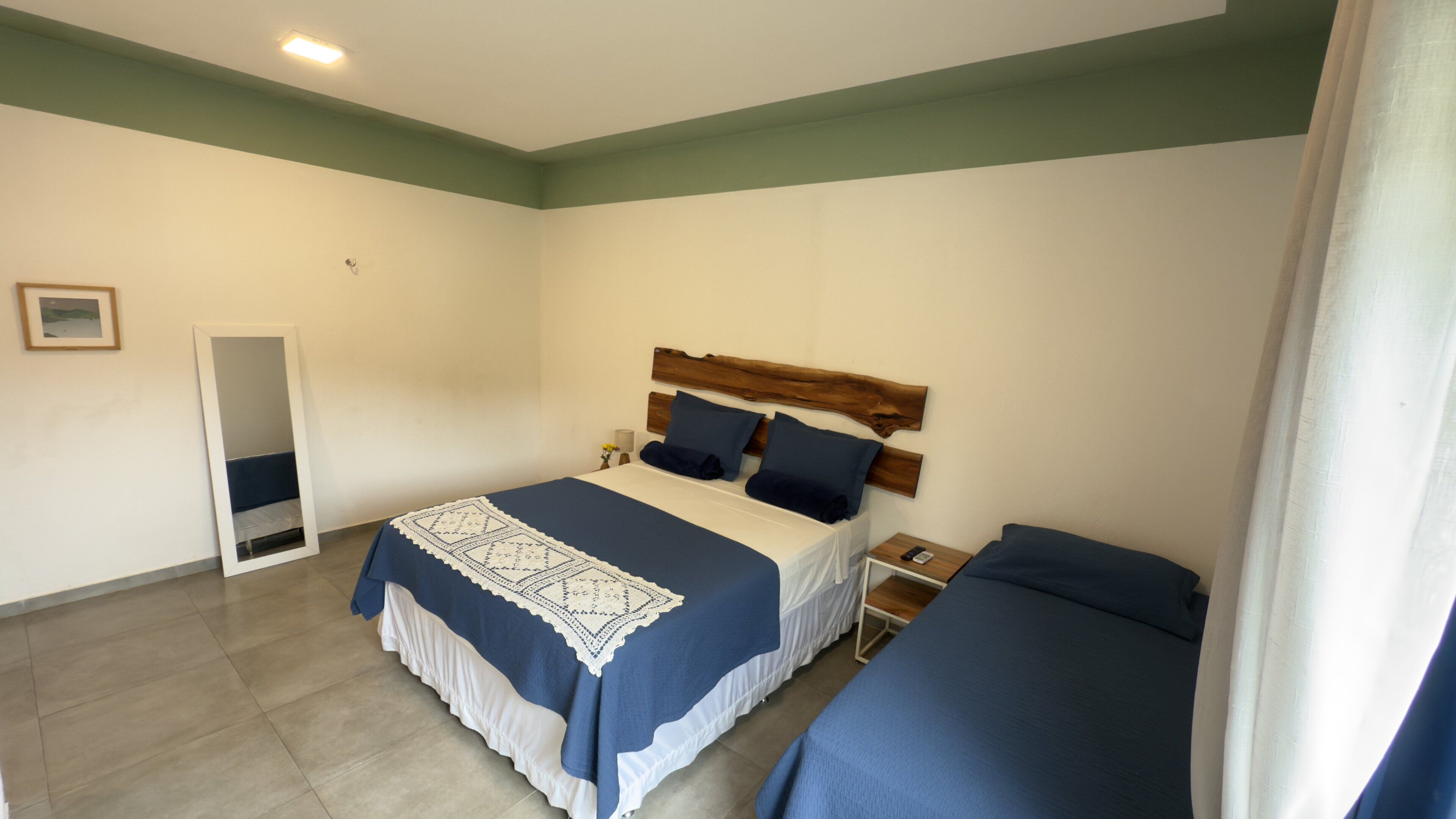A bedroom with a bed, bedside tables, a nightstand, and a mirror.