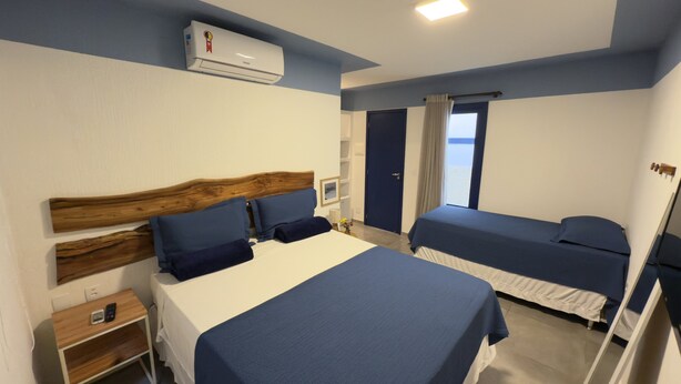 Une chambre d’hôtel avec deux lits, une tête de lit en bois, une table de chevet avec un téléphone et une fenêtre avec des rideaux.
