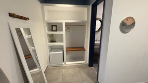 Un dressing avec des étagères ouvertes, une tringle et un miroir.
