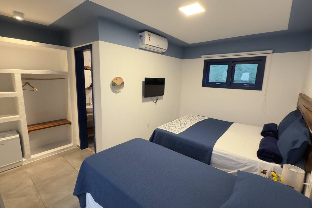 Een slaapkamer met twee bedden, een kast, een televisie en een raam.