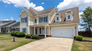 A two-story house with a front garage, a covered porch, and a well-maintained lawn. - Spacious 5BR Retreat Sleeps 14 Huge Yard! (Warner Robins)