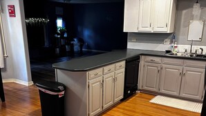 A modern kitchen with wooden flooring, white cabinets, and a black countertop. - Roomy 4-bed house in Springfield + Pet friendly + Gym + Workspace (Springfield)
