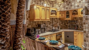 Une cuisine avec des carreaux décoratifs, des meubles en bois et un coin bar agrémenté de chaises en osier.