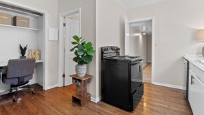 Une cuisine moderne avec un poêle noir, un plancher en bois et un petit tabouret en bois sur lequel est posée une plante en pot.