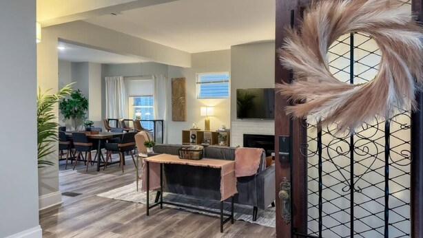 Un salon moderne comprenant un coin repas, une cheminée et une porte décorative ornée d’un motif de plumes.
