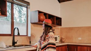 Een keuken met houten kastjes, een raam en een magnetron.