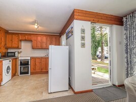 A compact kitchen with wooden cabinets, a washing machine, a refrigerator, and a microwave.