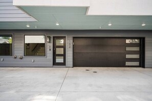 A modern garage with a large door, a small window, and a covered entryway.