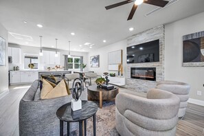 Ein modernes Wohnzimmer mit Kamin, grauen Sofas und einem Essbereich.