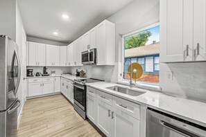 Cook breakfast for everyone before the day starts, with the fridge, range and dishwasher all within reach and the window letting the morning sun in. - 3BR Townhome~Rooftop Hot Tub~Skyline Views~Dallas (Dallas)